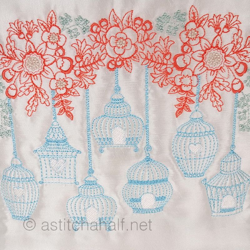Decorative pillow with floral and birdcage design on a light blue background