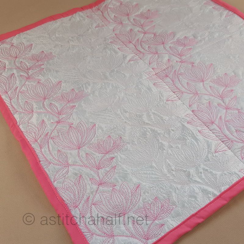 Pink pillow with heart patterns on a beige armchair in a bedroom setting.