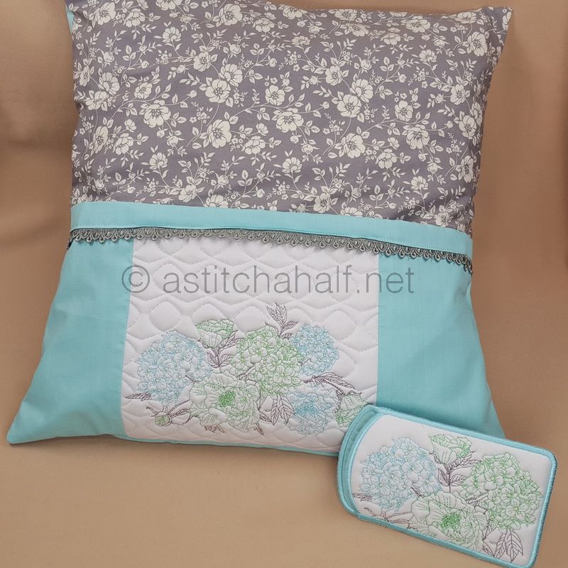 A reading pillow with a hydrangea pattern and eyeglasses placed on top of it, set against a beige background.