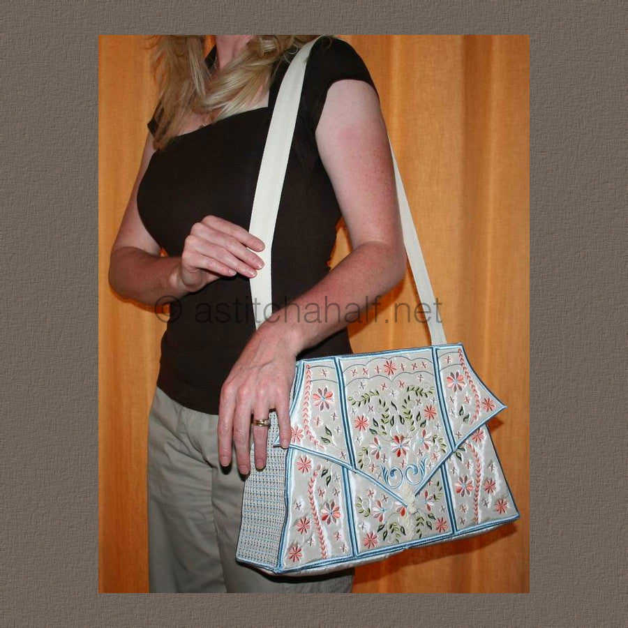 A person holding a multicolored floral tote bag with a white strap and blue trim.